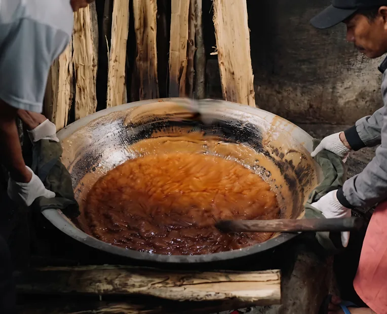 Arenga sap cooking down in a wide pan over a wood fire