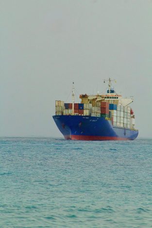 A large cargo ship filled with containers sailing on open waters.